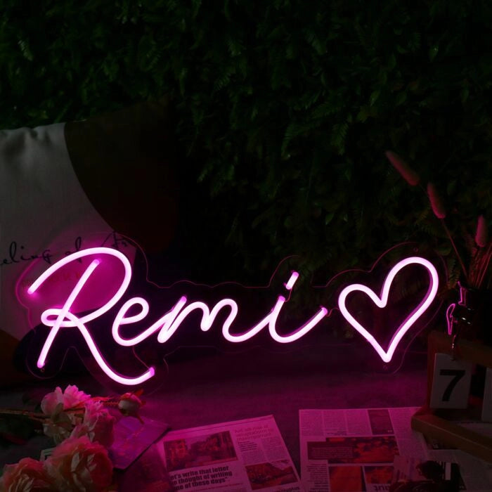"Remi Name LED Neon Sign by LEDNeons - glowing in stylish cursive font on a wall backdrop"