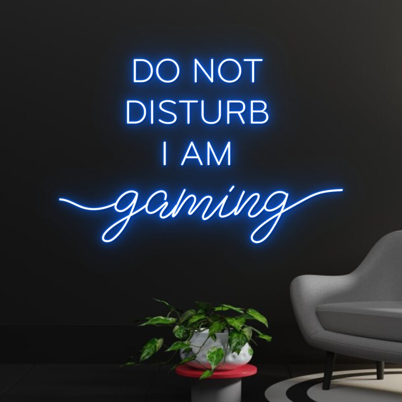 "Do Not Disturb I Am Gaming" LED Neon sign by LEDNeons -  lit up on a wall, adding bold style to a gamer’s room.