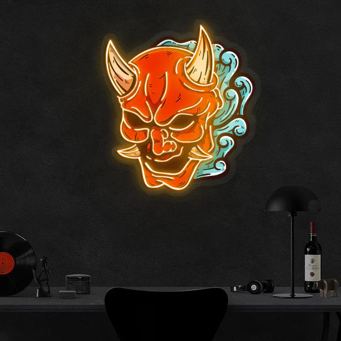 Bright neon sign of a red demon mask with horns and blue swirling flames, mounted on a dark wall above a Desk.
