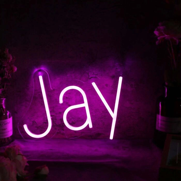 Jay Name LED Neon Sign by LEDNeons -  glowing in stylish cursive font on wall backdrop"