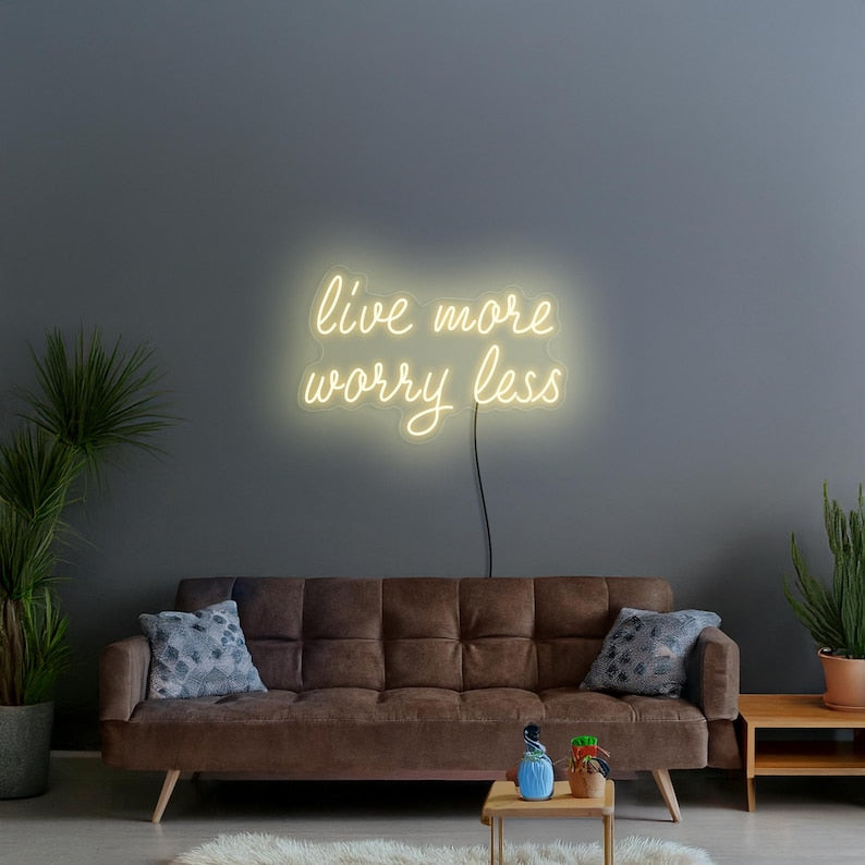 "Live More Worry Less" LED Neon sign by  LedNeons.com - glowing softly on a wall, creating a peaceful and uplifting ambiance.