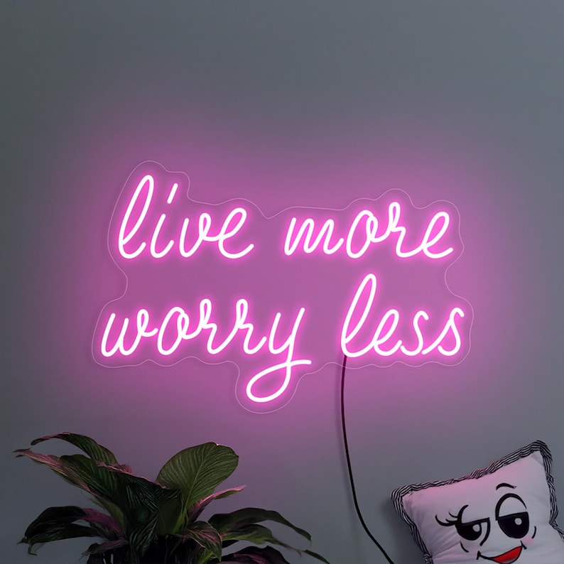"Live More Worry Less" LED Neon sign by LedNeons.com- glowing softly on a wall, creating a peaceful and uplifting ambiance.