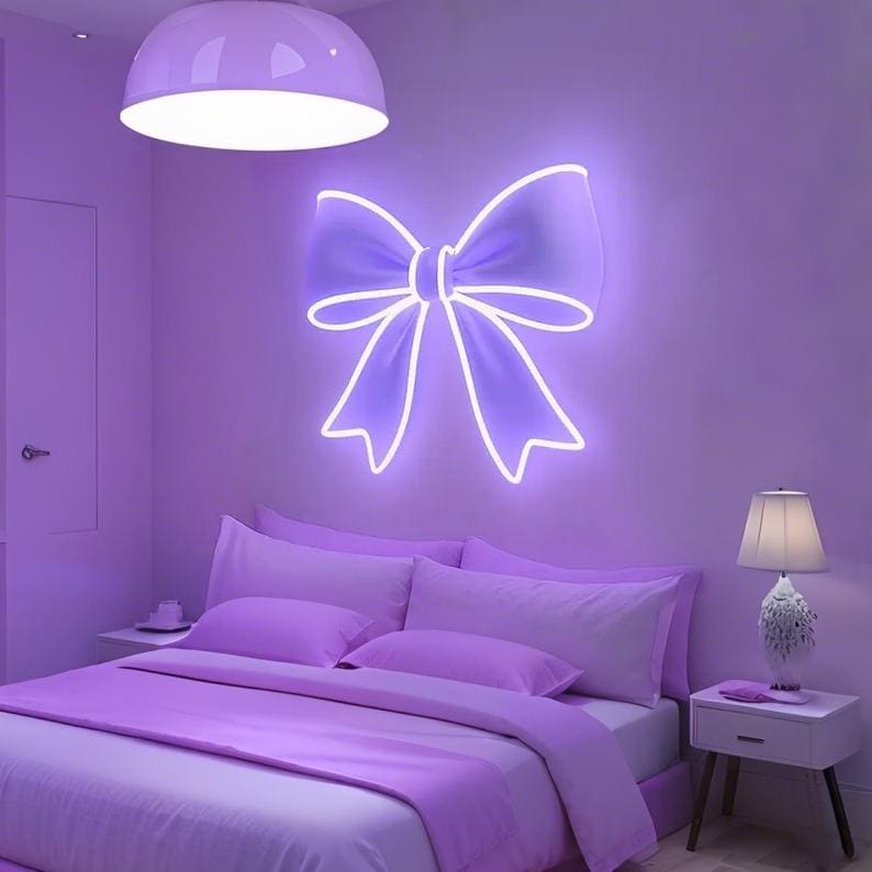 Pink bow-shaped LED Neon sign by LEDNeons - glowing softly on a wall, adding a cute and feminine touch to the decor.