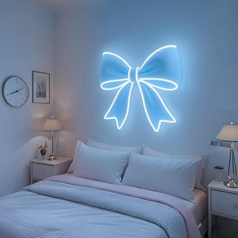 Pink bow-shaped LED Neon sign by LEDNeons - glowing softly on a wall, adding a cute and feminine touch to the decor.