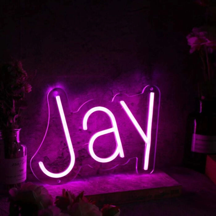 Jay Name LED Neon Sign by LEDNeons -  glowing in stylish cursive font on wall backdrop"